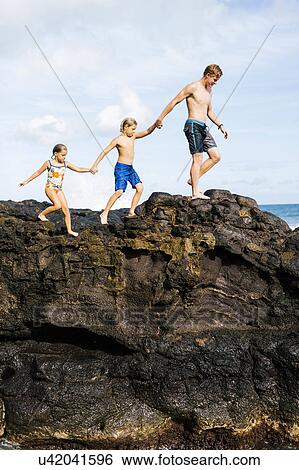 Young man walking on rock with kids (6-7, 8-9) View Large Photo Image Stock Photograph - Young man walking on rock with kids (6-7, 8-9). Fotosearch