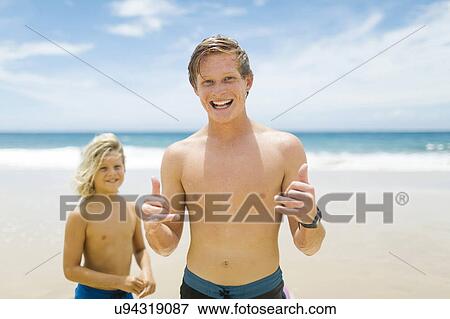 Young man with younger brother (4-5) playing at beach View Large Photo Image Stock Photo - Young man with younger brother (4-5) playing at beach. Fotosearch