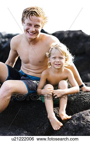 Stock Photograph - Young man with younger brother (4-5) sitting on rocks. Fotosearch