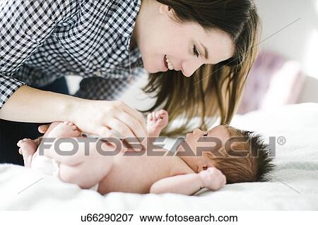 Young mother with baby girl (0-1 months) lying on bed View Large Photo Image Stock Photo - Young mother with baby girl (0-1 months) lying on bed. Fotosearch