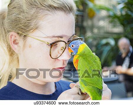 Stock Image - Young woman holding Rainbow lorikeet (Trichoglossus haematodus moluccanus). Fotosearch