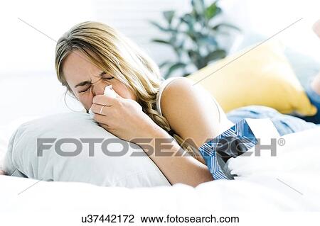 Young woman lying on bed and blowing nose View Large Photo Image Stock Image - Young woman lying on bed and blowing nose. Fotosearch