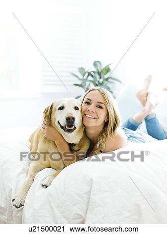 Stock Image - Young woman playing with golden retriever. Fotosearch