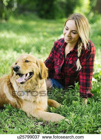 Stock Photo - Young woman playing with golden retriever. Fotosearch