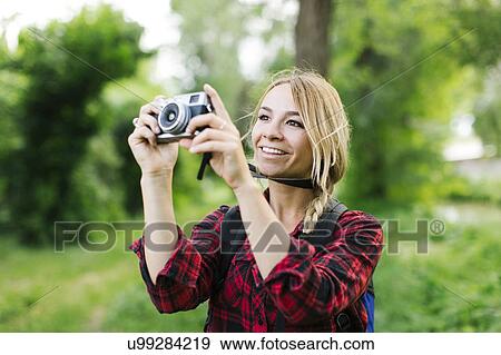 Stock Photo - Young woman taking pictures in park. Fotosearch
