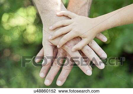 Stock Image - Adult and child's hands on top of each other.. Fotosearch