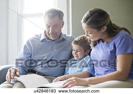Boy reading a book with his grandfather and his mother. View Large Photo Image Stock Image - Boy reading a book with his grandfather and his mother.. Fotosearch