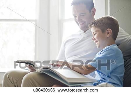 Stock Photograph - Boy reading book with his father.. Fotosearch