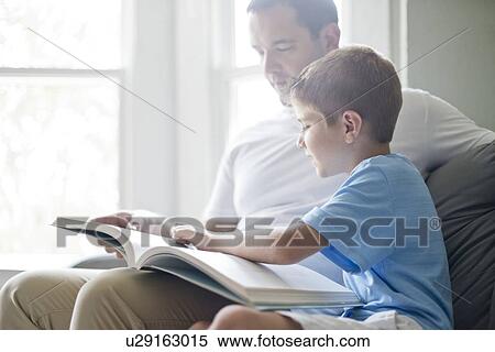 Stock Photography - Boy reading book with his father.. Fotosearch