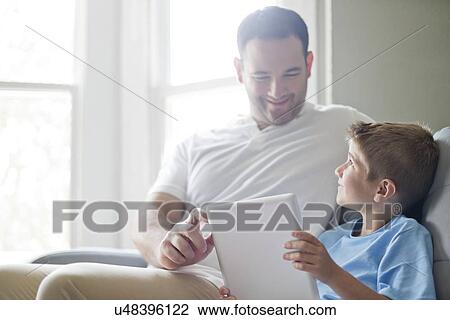 Stock Image - Boy using digital tablet with his father.. Fotosearch