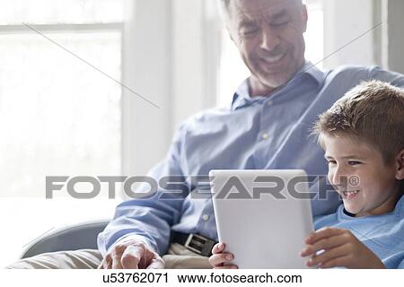 Stock Image - Boy using digital tablet with his grandfather.. Fotosearch
