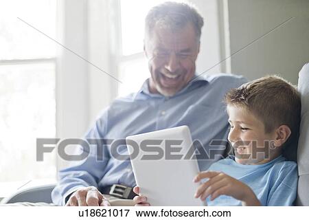 Stock Photo - Boy using digital tablet with his grandfather.. Fotosearch