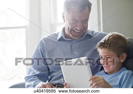 Stock Photography - Boy using digital tablet with his grandfather.. Fotosearch