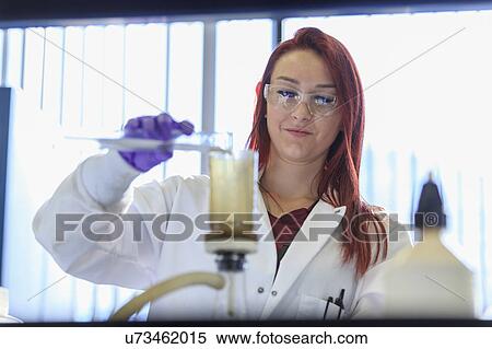 Stock Photography - Chemist adding sample to filtration strainer.. Fotosearch