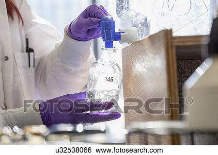 Stock Photograph - Chemist collecting reagent.. Fotosearch