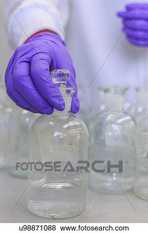 Stock Photo - Chemist holding reagent bottle.. Fotosearch