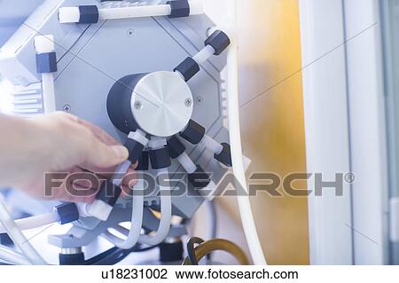 Stock Image - Chemist setting up a vacuum pump in a pharmaceutical laboratory.. Fotosearch