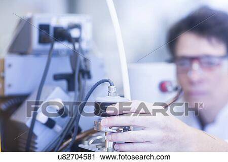 Stock Image - Chemist setting up a vacuum pump in a pharmaceutical laboratory.. Fotosearch