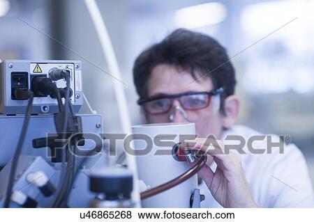 Stock Photo - Chemist setting up a vacuum pump in a pharmaceutical laboratory.. Fotosearch