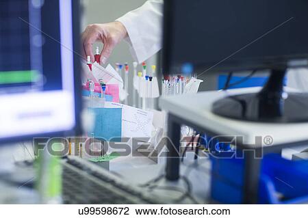 Stock Image - Chemist with NMR (nuclear magnetic resonance) spectroscopy phials in pharmaceutical laboratory.. Fotosearch