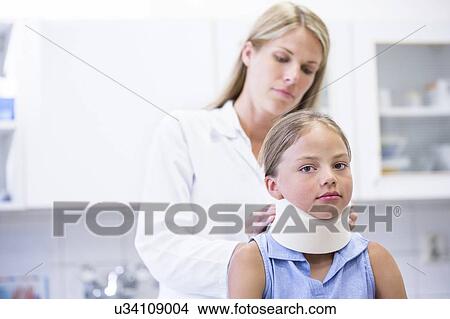 Picture - Doctor applying neck support to young girl.. Fotosearch