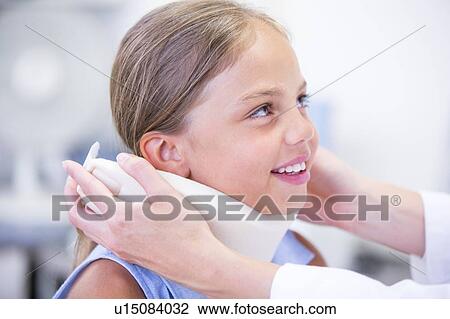 Stock Image - Doctor applying neck support to young girl.. Fotosearch