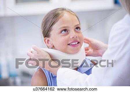 Stock Image - Doctor applying neck support to young girl.. Fotosearch