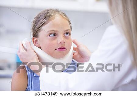 Stock Photo - Doctor applying neck support to young girl.. Fotosearch