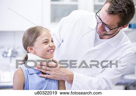 Stock Photo - Doctor applying neck support to young girl.. Fotosearch