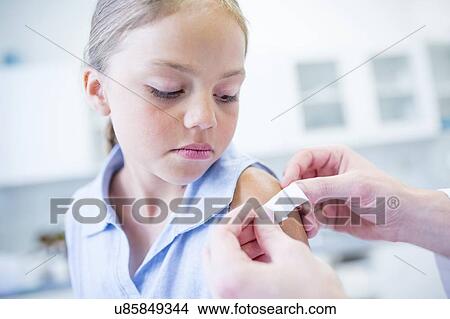 Picture - Doctor applying plaster to child's arm after vaccination.. Fotosearch