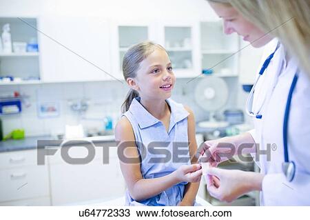 Stock Image - Doctor applying plaster to girl's finger.. Fotosearch