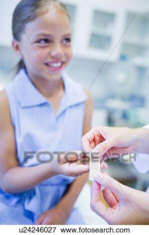 Stock Photo - Doctor applying plaster to girl's finger.. Fotosearch