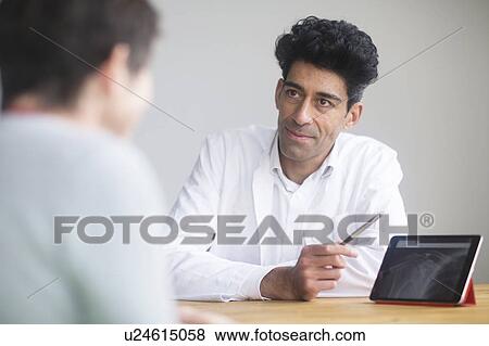 Doctor discussing X-ray with patient View Large Photo Image Stock Photo - Doctor discussing X-ray with patient. Fotosearch