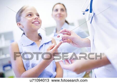 Stock Image - Doctor giving young girl a finger prick test.. Fotosearch