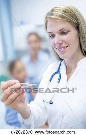 Doctor looking at thermometer. View Large Photo Image Stock Image - Doctor looking at thermometer.. Fotosearch
