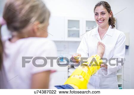 Stock Image - Doctor putting yellow leg brace on girl.. Fotosearch
