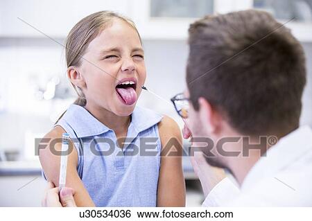 Stock Photograph - Doctor taking a swab from a young girl's mouth.. Fotosearch