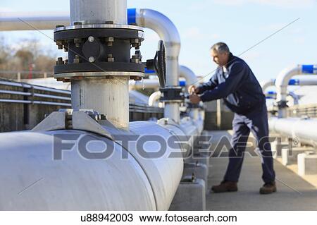 Stock Image - Engineer adjusting water flow control valve.. Fotosearch