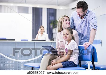 Family in medical waiting room, girl smiling towards camera. View Large Photo Image Stock Photo - Family in medical waiting room, girl smiling towards camera.. Fotosearch