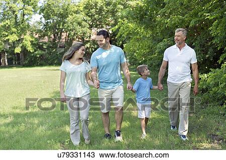 Stock Image - Family walking in park holding hands.. Fotosearch