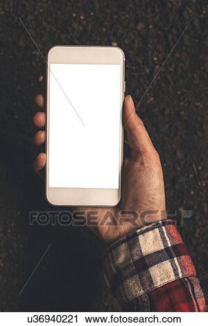 Stock Image - Farmer holding smartphone over soil. Fotosearch