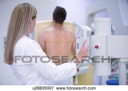 Stock Photo - Female doctor X-raying man's chest.. Fotosearch