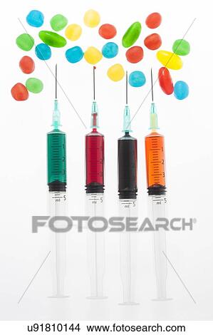 Picture - Four syringes with colourful liquid spots, studio shot.. Fotosearch