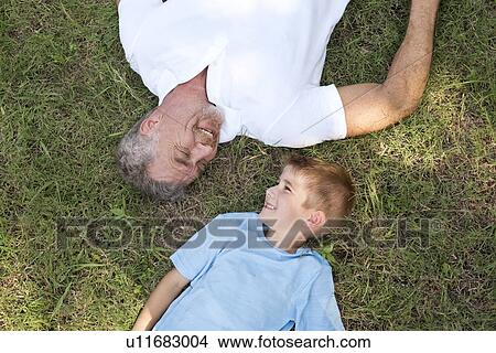 Grandfather and grandson lying on grass, high angle. View Large Photo Image Picture - Grandfather and grandson lying on grass, high angle.. Fotosearch