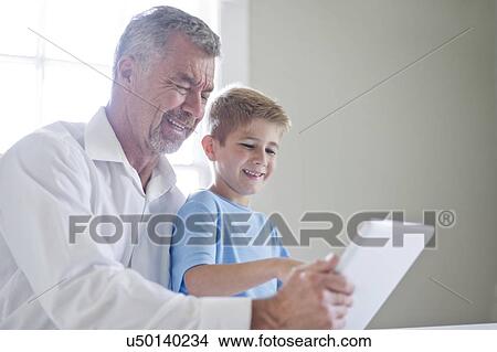 Picture - Grandfather and grandson using digital tablet.. Fotosearch