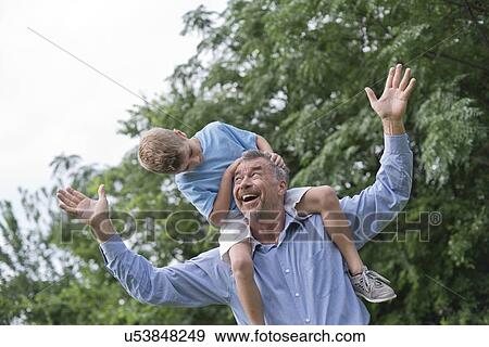 Grandfather carrying grandson on shoulders with arms out. View Large Photo Image Stock Photo - Grandfather carrying grandson on shoulders with arms out.. Fotosearch