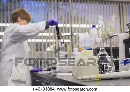 Picture - Lab technician adding reagent to sample while measuring pH.. Fotosearch