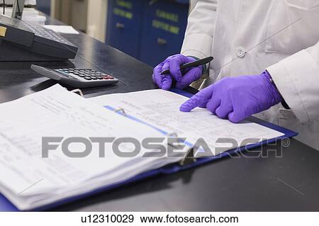 Stock Photo - Lab technician recording data from sample test.. Fotosearch