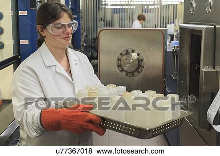 Stock Photo - Lab technician removing sample bottles from sterilization tank.. Fotosearch