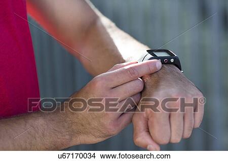 Picture - Male athlete checking sports watch, close up.. Fotosearch